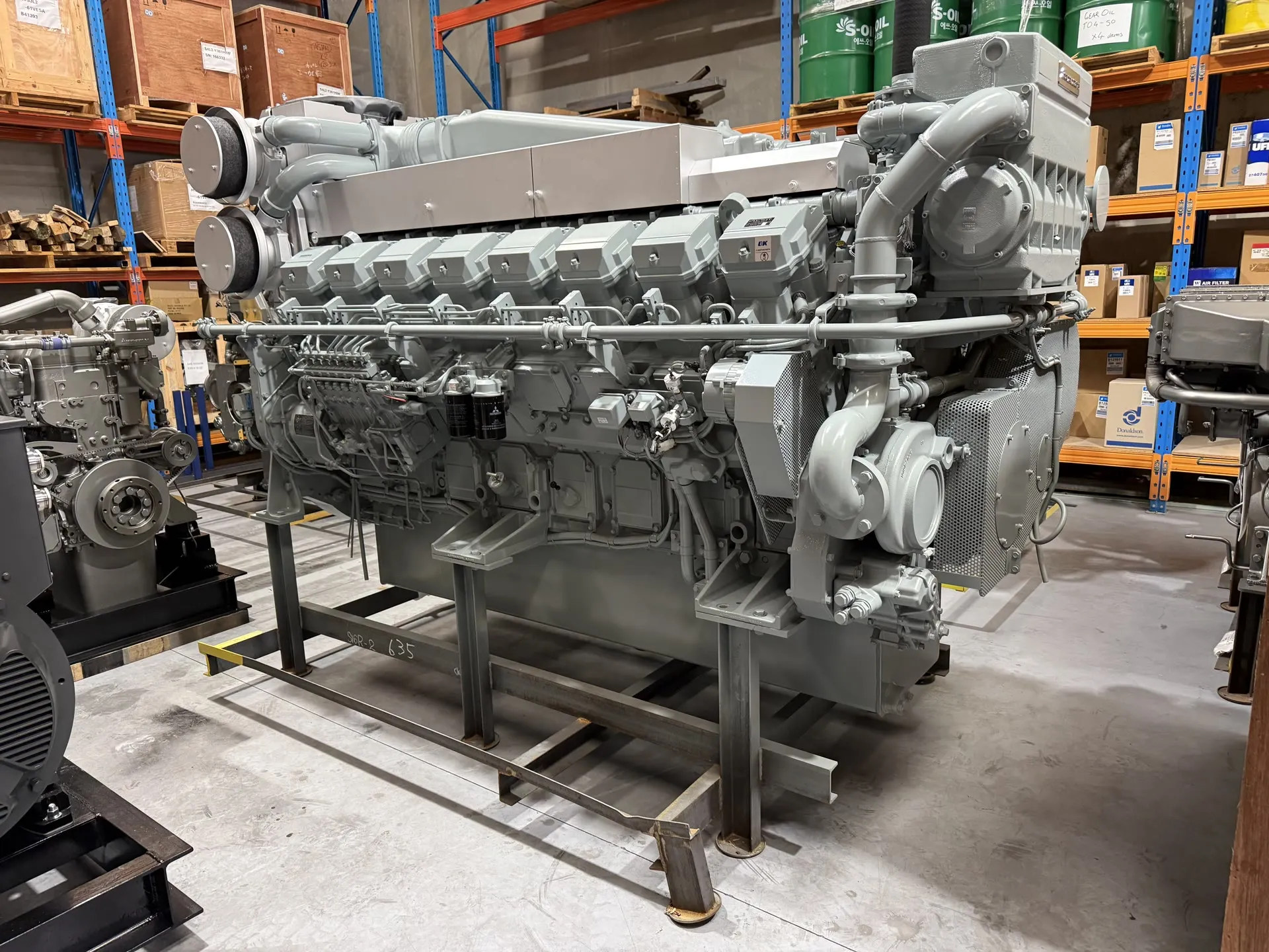A large multi-cylinder Mitsubishi marine diesel engine on a fabrication stand in OPS's Wangara warehouse